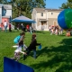 Children chase a large beach ball in the foreground as families mingle with community partners in the back.